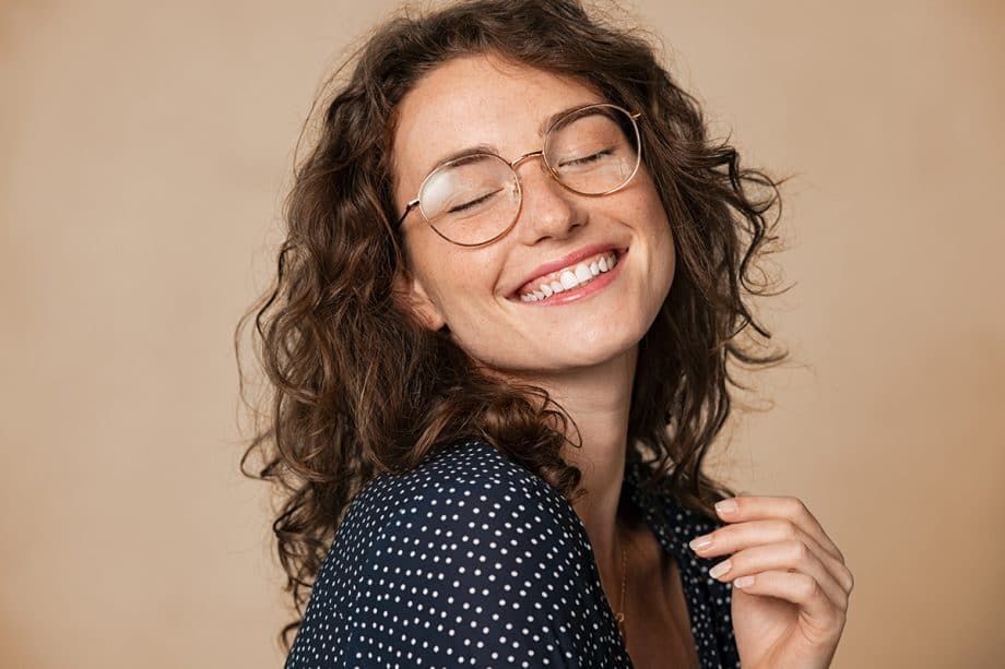 woman with wavy hair and glasses smiles